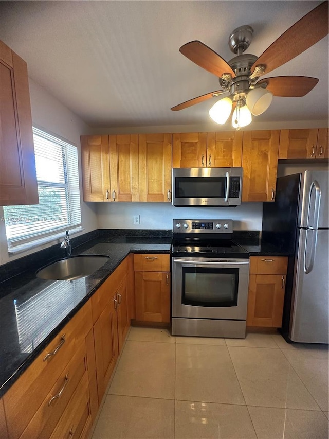 kitchen featuring stainless steel appliances, dark stone countertops, sink, and light tile patterned floors