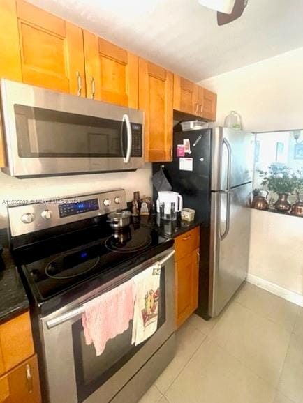 kitchen featuring ceiling fan, stainless steel appliances, and light tile patterned floors