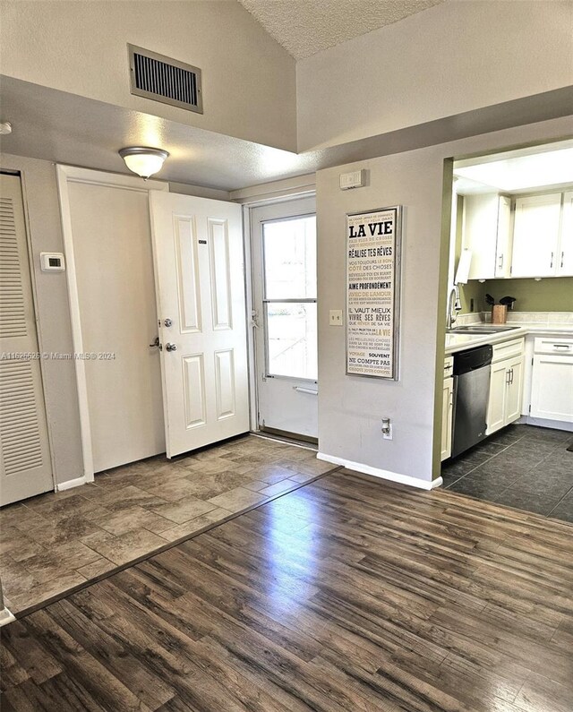 tiled entryway featuring lofted ceiling, sink, and a textured ceiling