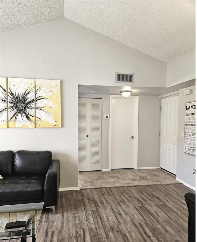 living room featuring wood-type flooring, vaulted ceiling, and a textured ceiling