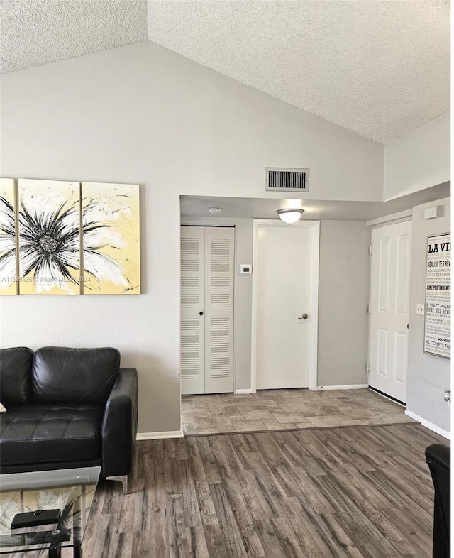 interior space featuring lofted ceiling, dark hardwood / wood-style floors, and a textured ceiling