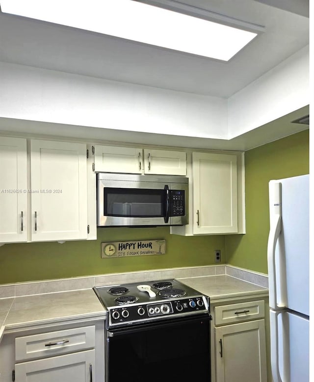 kitchen featuring white cabinetry, black electric range, and white refrigerator