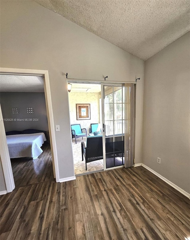 unfurnished room with lofted ceiling, dark hardwood / wood-style floors, and a textured ceiling