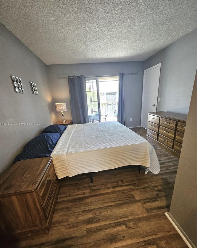 bedroom featuring access to exterior, a textured ceiling, and hardwood / wood-style floors