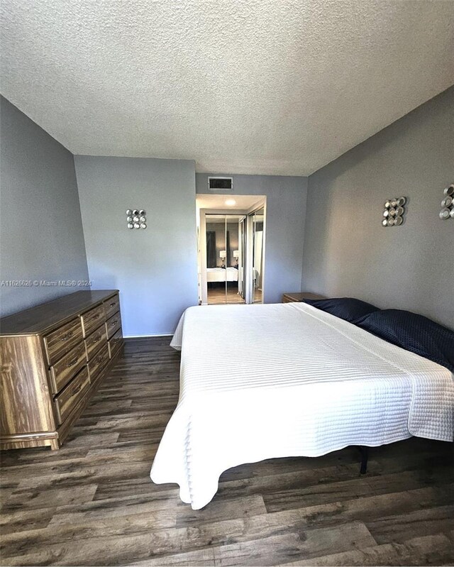 bedroom featuring dark hardwood / wood-style flooring and a textured ceiling