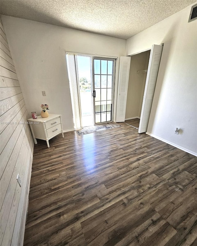 interior space with dark wood-type flooring, a textured ceiling, a closet, and access to outside