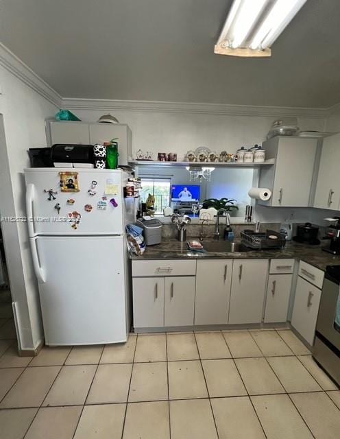 kitchen with white cabinetry, ornamental molding, white fridge, stove, and light tile patterned floors