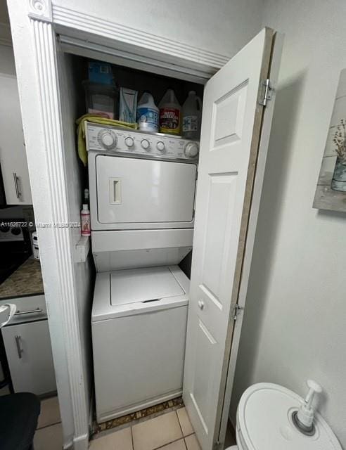 laundry area featuring stacked washer and clothes dryer and light tile patterned floors