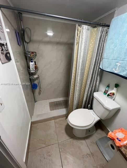 bathroom with toilet, tile patterned floors, and a shower with curtain