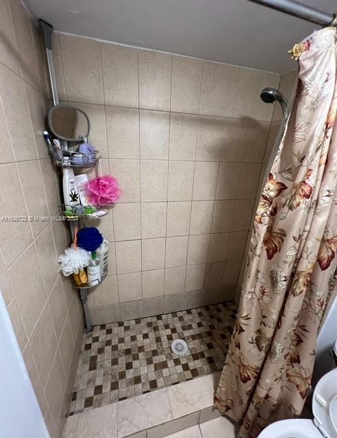 bathroom featuring tile patterned flooring, curtained shower, and toilet