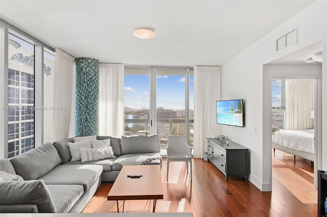 living room featuring dark wood-type flooring, floor to ceiling windows, and a healthy amount of sunlight