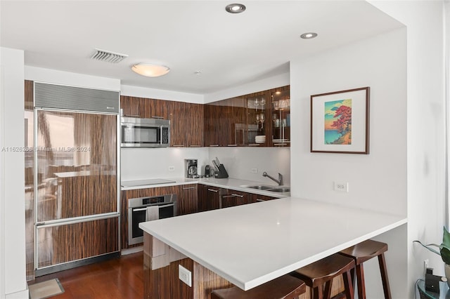 kitchen with sink, a kitchen breakfast bar, kitchen peninsula, and appliances with stainless steel finishes