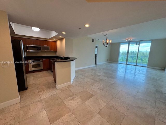 kitchen with stainless steel appliances, pendant lighting, sink, a wall of windows, and kitchen peninsula