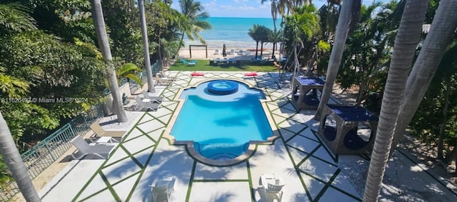 view of swimming pool featuring an in ground hot tub, a patio, and a water view