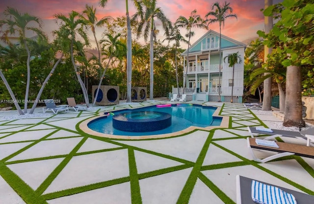 pool at dusk with an in ground hot tub and a patio