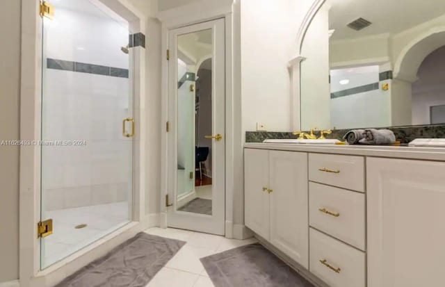 bathroom with a shower with door, vanity, and tile patterned floors