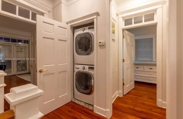 clothes washing area featuring dark hardwood / wood-style floors and stacked washing maching and dryer