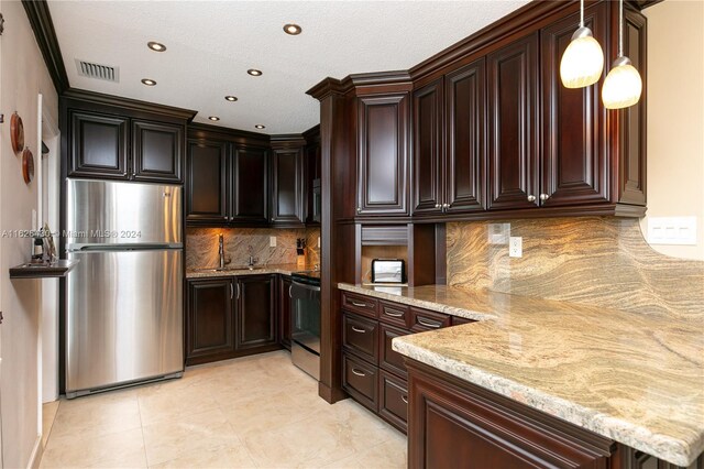 kitchen with range, tasteful backsplash, stainless steel refrigerator, light stone countertops, and pendant lighting