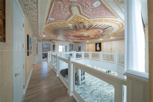 corridor with ornamental molding, light hardwood / wood-style flooring, and a tray ceiling