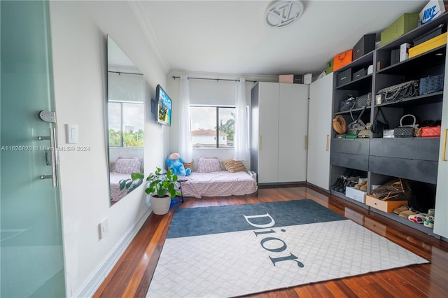 sitting room with ornamental molding and dark wood-type flooring