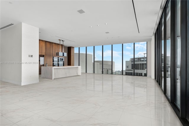 unfurnished living room featuring expansive windows, marble finish floor, and wood walls