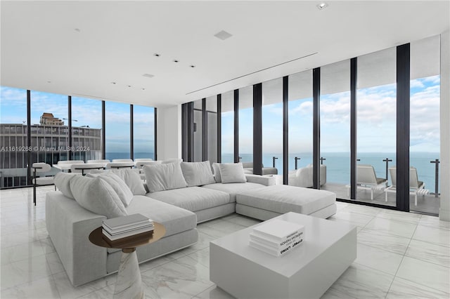 living area featuring floor to ceiling windows, a water view, and marble finish floor