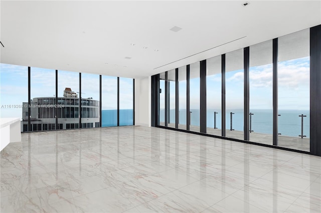 unfurnished room with a water view and a wall of windows