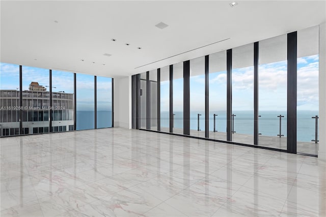 empty room featuring elevator, floor to ceiling windows, and a water view