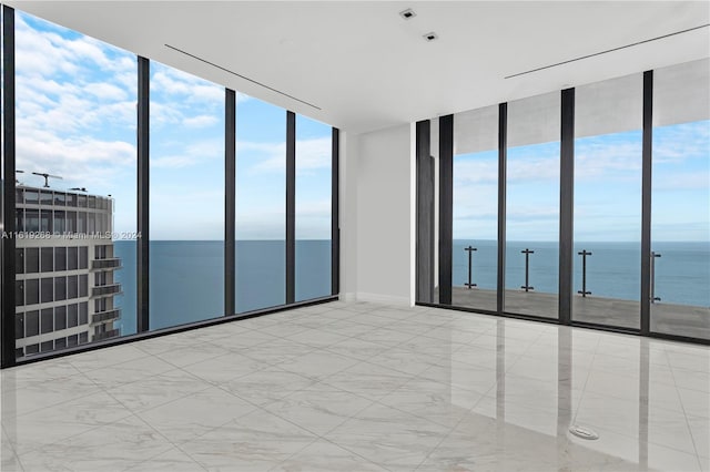 unfurnished room featuring a healthy amount of sunlight, a water view, and floor to ceiling windows