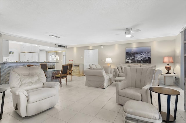 living room featuring ceiling fan, a textured ceiling, light tile patterned floors, and crown molding