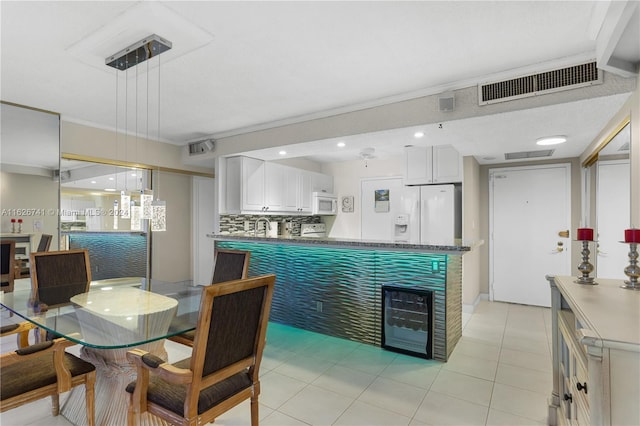 kitchen featuring white appliances, decorative light fixtures, white cabinetry, kitchen peninsula, and ornamental molding