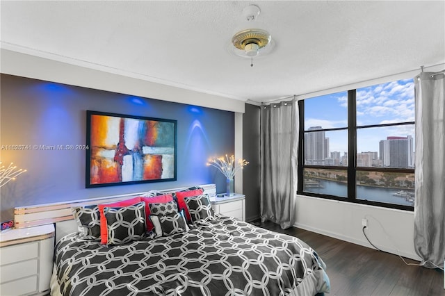 bedroom featuring a textured ceiling, dark hardwood / wood-style flooring, and ornamental molding