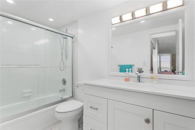 full bathroom featuring vanity, toilet, and bath / shower combo with glass door