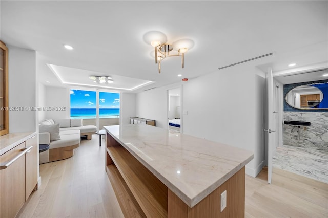 kitchen featuring a chandelier, a kitchen island, light wood-style flooring, and modern cabinets