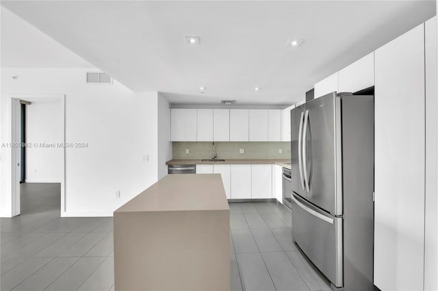 kitchen featuring backsplash, a center island, appliances with stainless steel finishes, and white cabinetry