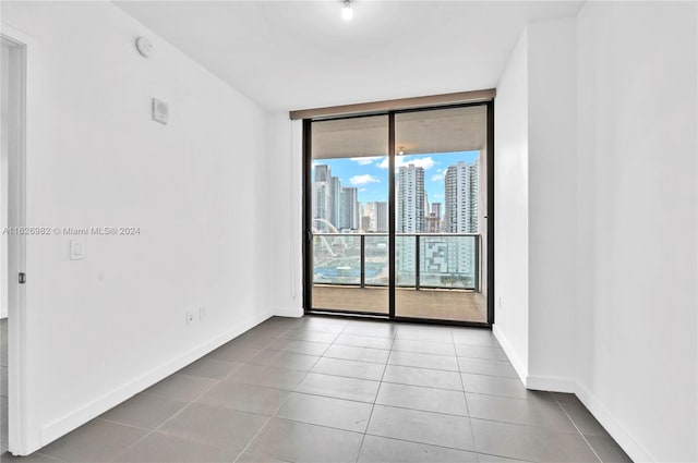 empty room with a wall of windows and light tile patterned floors