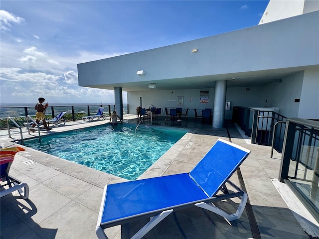 view of pool with a patio and a water view