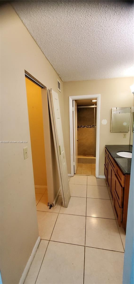 corridor with a textured ceiling and light tile patterned flooring