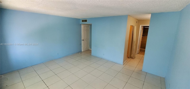 tiled empty room with a textured ceiling