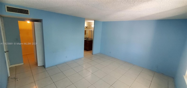 tiled empty room featuring a textured ceiling