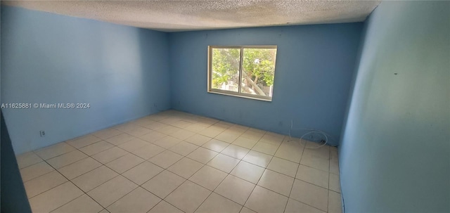 tiled empty room with a textured ceiling