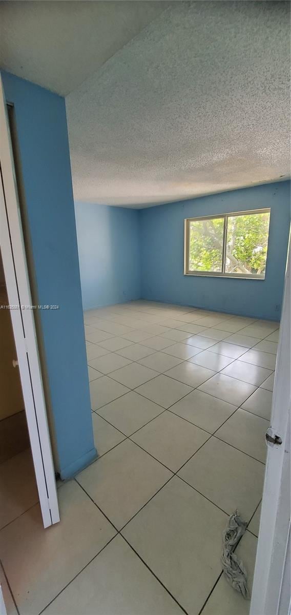 tiled spare room featuring a textured ceiling