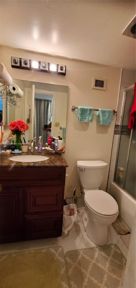 full bathroom featuring vanity, toilet, and shower / bath combination with glass door