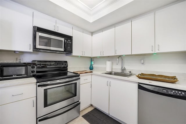 kitchen featuring a sink, white cabinets, light countertops, appliances with stainless steel finishes, and crown molding