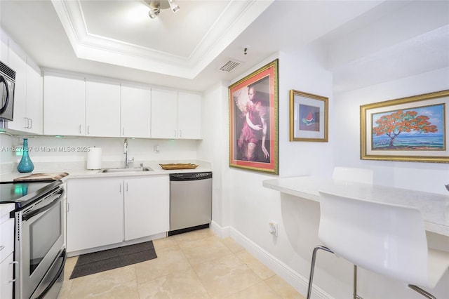 kitchen featuring a sink, visible vents, ornamental molding, appliances with stainless steel finishes, and a tray ceiling