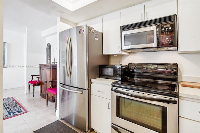 kitchen featuring light countertops, appliances with stainless steel finishes, light tile patterned floors, and white cabinets