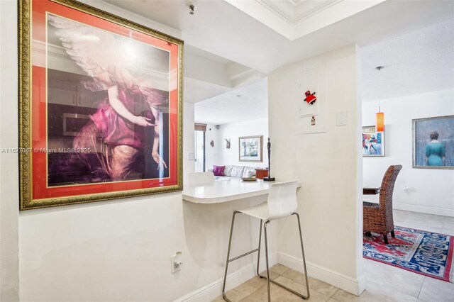 hallway with light tile patterned flooring and a tray ceiling