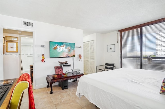 bedroom with light tile patterned flooring, baseboards, visible vents, and a closet