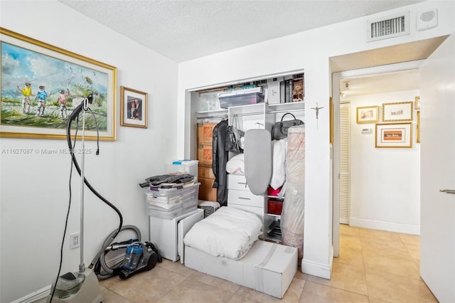 interior space with a textured ceiling, baseboards, visible vents, and tile patterned floors