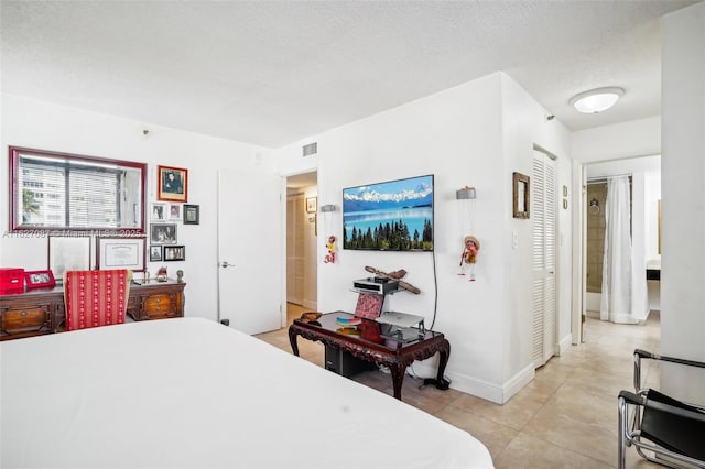 bedroom with light tile patterned floors, a textured ceiling, visible vents, and baseboards